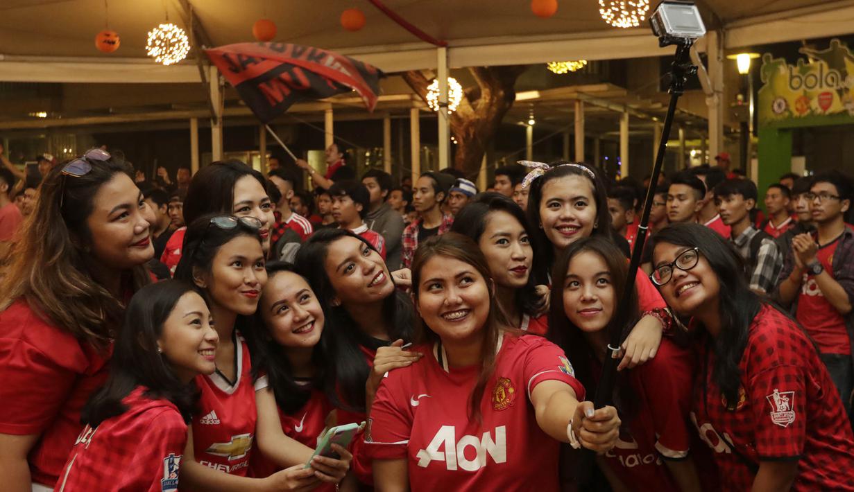 Para fans wanita melakukan selfie saat mendukung MU melawan City. (Bola.com/Vitalis Yogi Trisna)