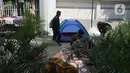 Pejalan kaki melintasi pencari suaka yang tinggal sementara di trotoar kantor UNHCR, Jalan Kebon Sirih, Jakarta, Sabtu (1/5/2021). Para pencari suaka itu menuntut Komisi Tinggi PBB untuk Pengungsi (UNHCR) meminta kejelasan atas status dan memperhatikan nasib mereka. (Liputan6.com/Herman Zakharia)