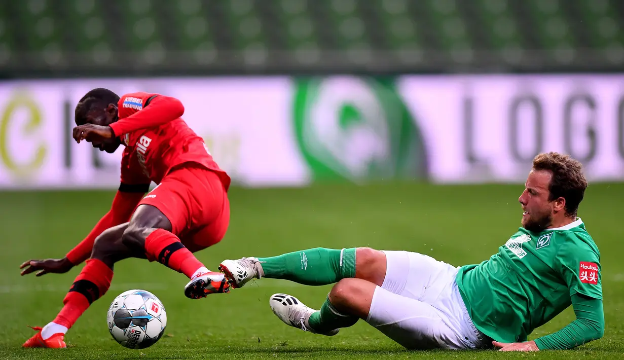 Pemain Werder Bremen Philipp Bargfrede (kanan) berebut bola dengan pemain Bayer Leverkusen Moussa Diaby dalam pertandingan Bundesliga di Bremen, Jerman, Senin (18/5/2020). Bayer Leverkusen menang 4-1. (Stuart FRANKLIN/POOL/AFP)
