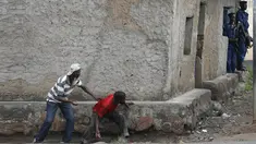 Pengunjuk rasa sembunyi dibalik dinding dengan membawa batu bersiap menyerang petugas di Bujumbura, Burundi, (20/5/2015). Kerusuhan dipicu protes terhadap Presiden Burundi Pierre Nkurunziza untuk upayanya menambah masa jabatan. (REUTERS/Goran Tomasevic)