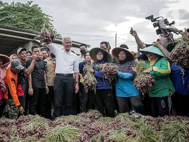 Calon presiden nomor urut 3 Ganjar Pranowo (tengah) mengangkat bawang merah saat bertemu dengan para petani bawang merah di Desa Kertabesuki, Kecamatan Wanasari, Kabupaten Brebes, Provinsi Jawa Tengah, Rabu (10/1/2024). Dalam kunjungannya, Ganjar melakukan diskusi singkat dengan sejumlah perwakilan petani. (Liputan6.com/Faizal Fanani)