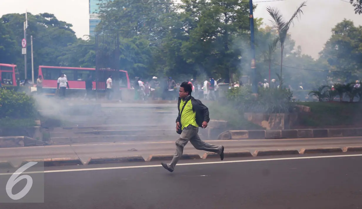 Seorang pria berlari menyelamatkan diri saat bentrok aparat kepolisian dengan massa yang berdemontrasi menuntut KPK segera mengusut Ahok yang diduga terlibat korupsi di RS Sumber Waras, Jakarta, Jumat (20/5). (Liputan6.com/Yoppy Renato)
