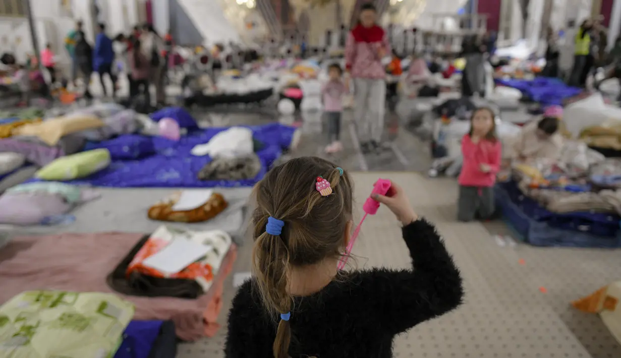 Seorang pengungsi anak yang melarikan diri dari invasi Rusia dari negara tetangga Ukraina bermain dengan mainan gelembung sabun di dalam ballroom yang diubah menjadi tempat penampungan pengungsi darurat di hotel & spa bintang 4, di Suceava, Rumania, 4 Maret 2022. (AP Photo/Andreea Alexandru)