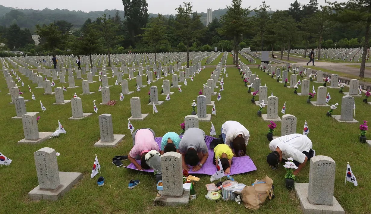 Warga Korsel, Park Tae-in dan keluarganya membungkuk memberi hormat di depan nisan saudaranya pada Memorial Day di Pemakaman Nasional Seoul, Kamis (6/6/2019). Memorial Day didedikasikan untuk mengingat prajurit dan warga sipil yang gugur selama perang Korea antara 1950-1953. (AP/Ahn Young-joon)