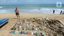 <p>Wisatawan asal Belanda menata sampah sandal dan sepatu yang dia kumpulkan dari Pantai Kuta. (merdeka.com/Arie Basuki)</p>