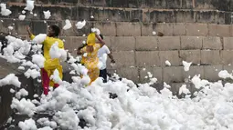 Orang-orang mengambil gambar dekat busa yang memenuhi sungai Yamuna di New Delhi, 23 September 2018. Sungai yang juga dianggap suci oleh umat Hindu India ini kini tercemar hebat, salah satunya akibat busa polusi yang memenuhinya. (AFP/Dominique FAGET)