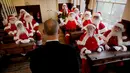 Sejumlah pria mengenakan kostum Santa Claus terlihat beradegan sedang belajar saat sesi pemotretan di Ragged School Museum di London (16/11). Sekolah ini bertujuan menjadikan 'Santa Claus' untuk kepentingan komersial. (AP Photo/Matt Dunham)