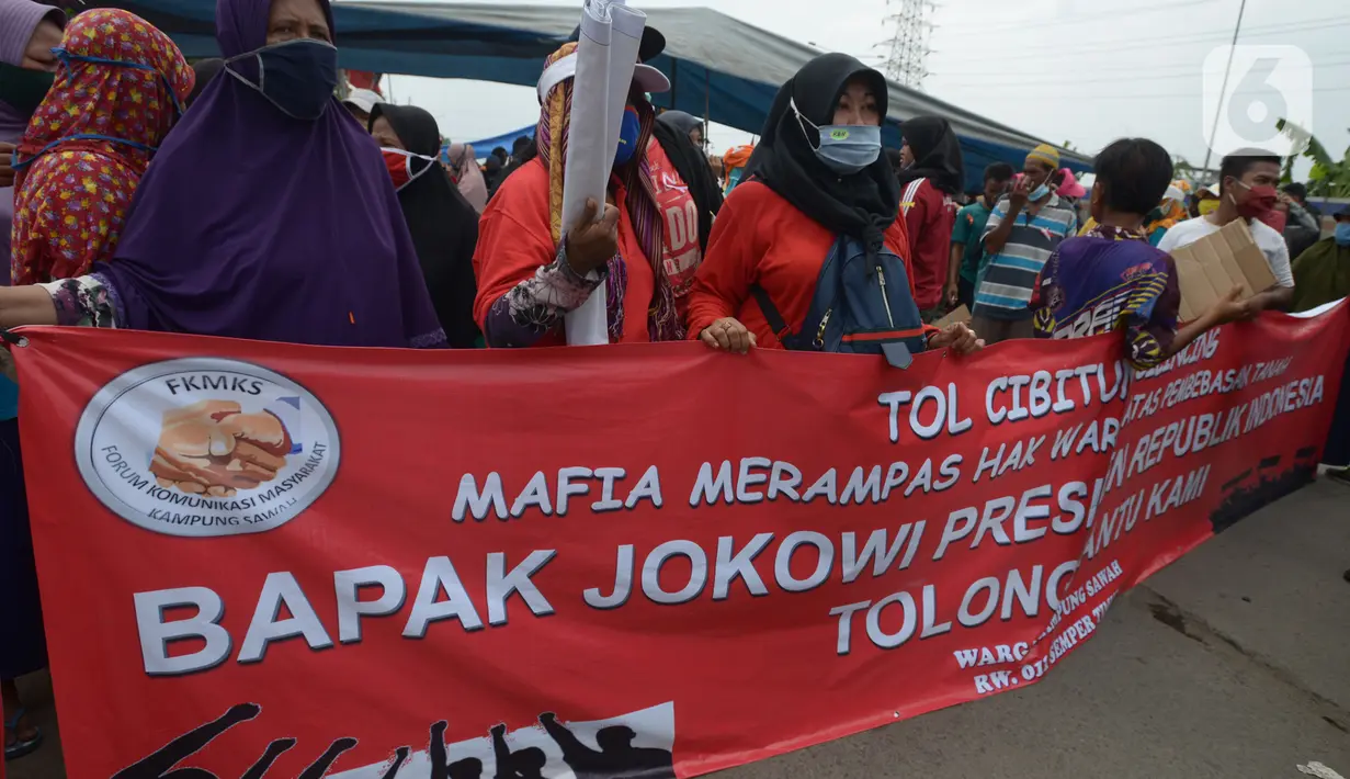 Warga Kampung Sawah membentangkan spanduk saat melakukan aksi dengan menutup akses jalan Cakung Cilincing, Jakarta, Rabu (18/11/2020). Aksi tutup jalan ini bentuk protes warga atas hak tanahnya yang terkena proyek pembangunan jalan tol Cakung Cilincing (Cacing)-Cibitung. (merdeka.com/Imam Buhori)