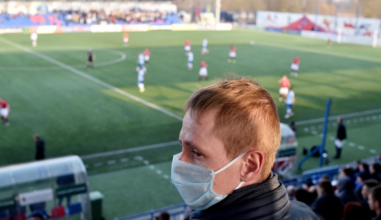 Suporter menggunakan masker saat menonton pertandingan antara FC Minsk melawan FC Dinamo-Minsk pada laga Liga Belarusia, Sabtu (28/3/2020). Di tengah wabah virus Corona, Liga Belarusia tetap digelar seperti biasa bahkan tetap dipadati suporternya. (AFP/Sergei Gapon)