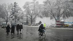 Seorang pria mengendarai sepedanya di sepanjang jalan saat hujan salju lebat di Kabul (4/1/2022). Beberapa kecelakaan terjadi pada Senin (3/1) di tengah kondisi lalu lintas yang kacau setelah hujan salju lebat. (AFP/Mohd Rasfan)