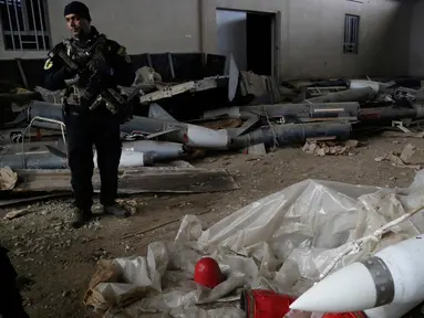 Pasukan khusus Irak berjaga dekat rudal yang ditemukan di sebuah gudang senjata milik ISIS di sisi timur Mosul, Sabtu (28/1). Gudang itu berisi puluhan roket peninggalan mantan diktator Irak Saddam Hussein dan gas mustard. (AP Photo/Khalid Mohammed)