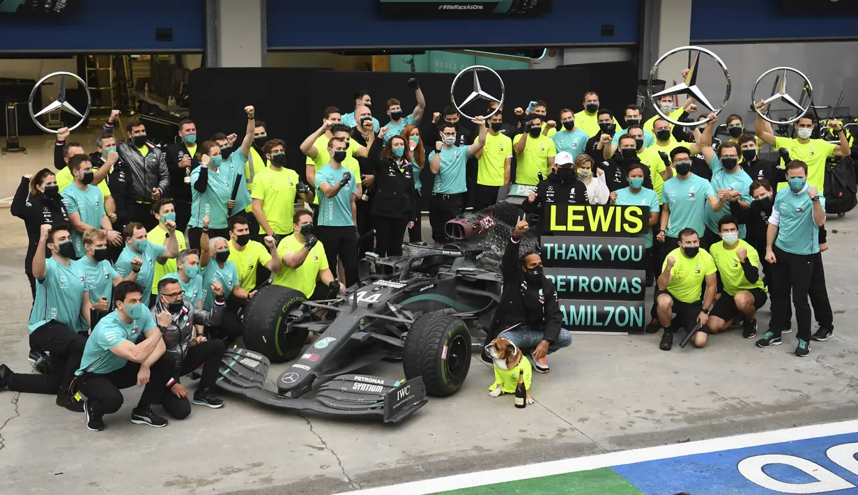 Pembalap Mercedes Lewis Hamilton berpose bersama timnya saat merayakan kemenangannya setelah memenangkan Grand Prix Formula Satu Turki di arena pacuan kuda Istanbul Park di Istanbul, Minggu (15/11/2020). (Clive Mason/Pool via AP)