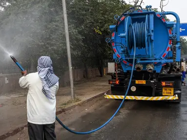 Petugas menyemprotkan air ke pohon-pohon di pinggir jalan New Delhi, India, Rabu (6/11/2019). Hal tersebut dilakukan dalam upaya untuk mengurangi polusi udara dengan memerangi akumulasi debu. (Photo by Prakash SINGH / AFP)