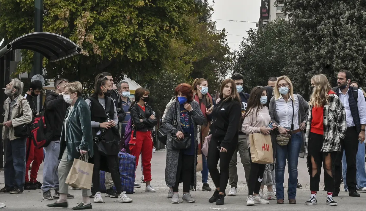 Orang-orang beberapa mengenakan masker, berkumpul di dekat halte bus di pusat Athena, Selasa (9/11/2021). Yunani mencatat lonjakan kasus dan kematian Covid-19 serta peningkatan penerimaan ICU, meskipun ada pembatasan baru dan kampanye untuk meningkatkan vaksinasi. (Louisa GOULIAMAKI/AFP)