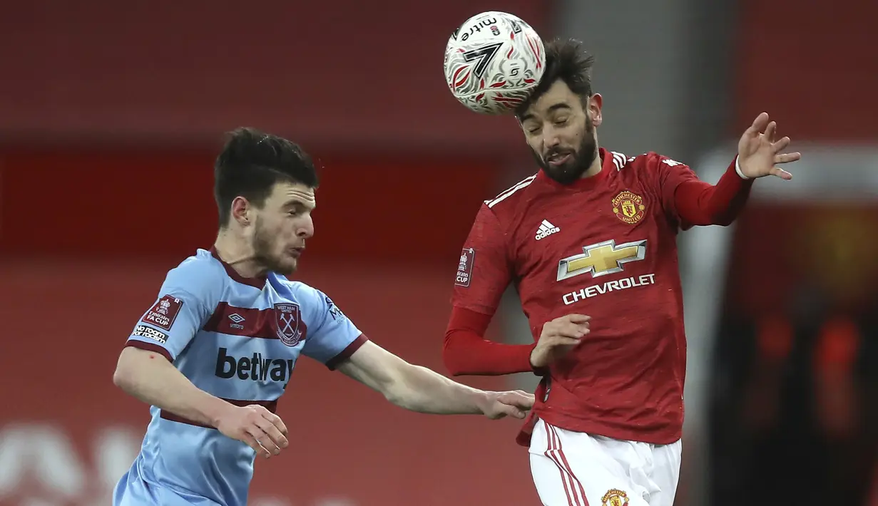 Gelandang Manchester United, Bruno Fernandes berebut bola udara dengan bek West Ham, Declan Rice pada pertandingan perdelapan final Piala FA 2020/2021 di Old Trafford, Inggris (10/2/2021). MU menang tipis atas West Ham 1-0. (Martin Rickett/Pool via AP)