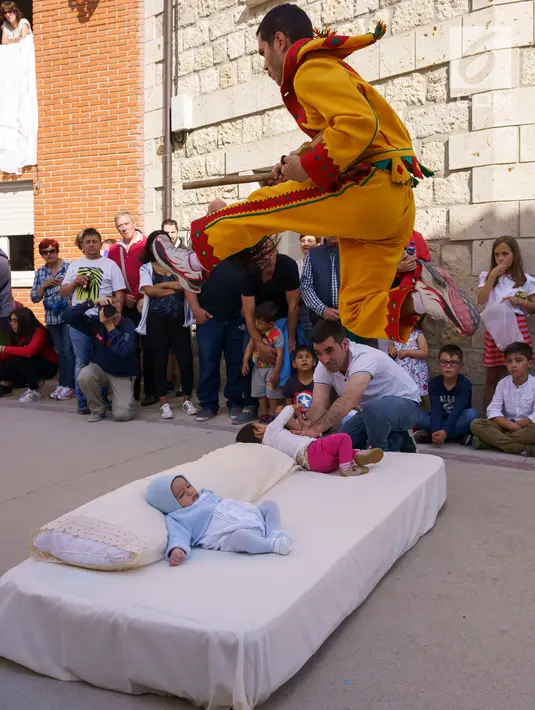 Pria berkostum setan melompati bayi-bayi yang terlentang di atas matras selama tradisi El Salto del Colacho di desa Castrillo de Murcia, Spanyol, Minggu (3/6). Tindakan ini bermakna untuk membersihkan bayi dari roh-roh jahat. (AFP/CESAR MANSO)