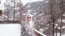 Berpose di hamparan salju Swiss, istri Rezky Aditya ini tampak anggun berbalut dress dan hijab monokrom.