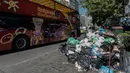 Sebuah bus wisata melintas dekat tumpukan sampah di pusat kota Athena, Yunani, Kamis (22/6). Ribuan petugas kebersihan melakukan pemogokan sejak awal pekan ini karena cemas terancam terkena PHK setelah kontraknya berakhir.  (ELEFTHERIOS ELIS/AFP)