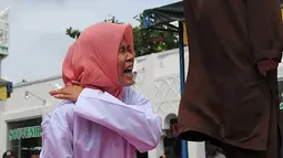 Nur Elita tampak meringis kesakitan saat petugas menyabetkan rotan ke punggungnya di halaman Masjid Baiturrahim, Ulee Lheue, Banda Aceh, Senin (28/12). Nur yang merupakan terpidana kasus khalwat mendapat hukuman 5 kali cambukan (AFP/dailymail.co.uk)