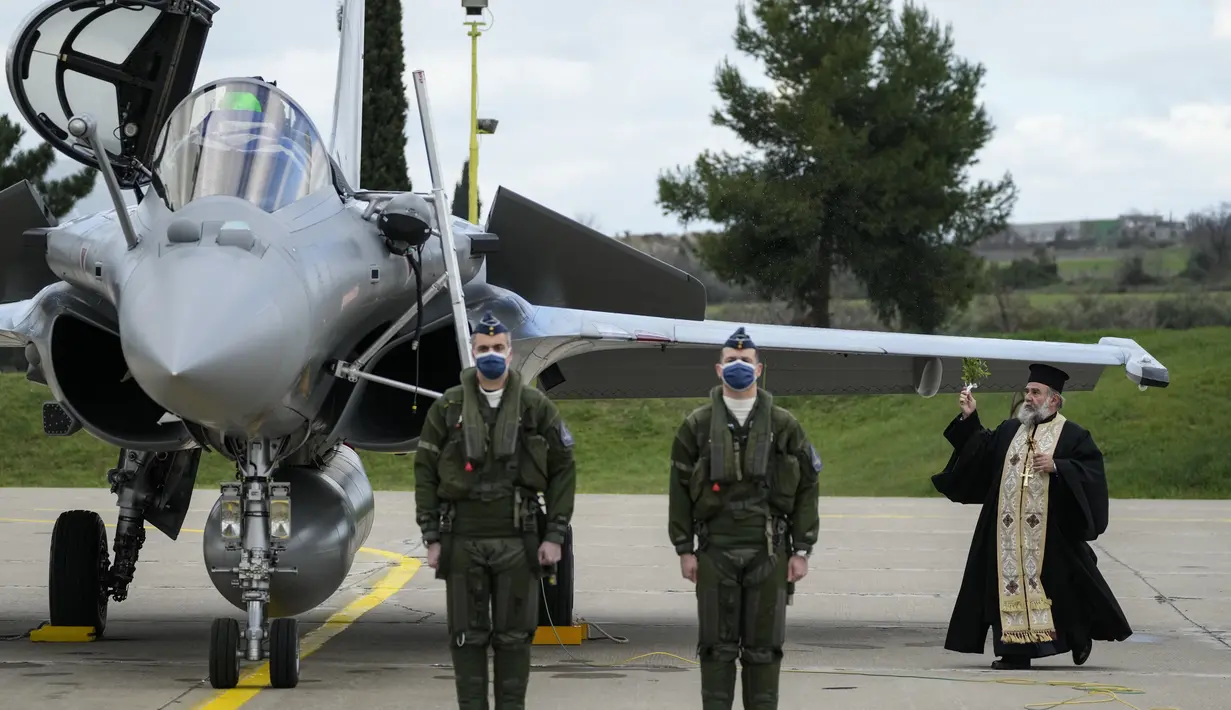 Pendeta Ortodoks Yunani memberkati jet tempur Rafale, dalam upacara kedatangan jet Rafale pertama dari Prancis, di Tanagra, Yunani (19/1/2022). Yunani menerima enam jet tempur Rafale pertama dari Prancis yang dibeli berdasarkan kesepakatan pertahanan dengan Prancis. (AP Photo/Thanassis Stavrakis)