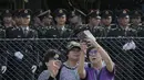 Sejumlah warga berpose di dekat barisan tentara saat upacara peringatan 20 tahun serah terima Hong Kong dari pemerintah Inggris ke China, di Hong Kong, Jumat (30/6). (AP Photo)