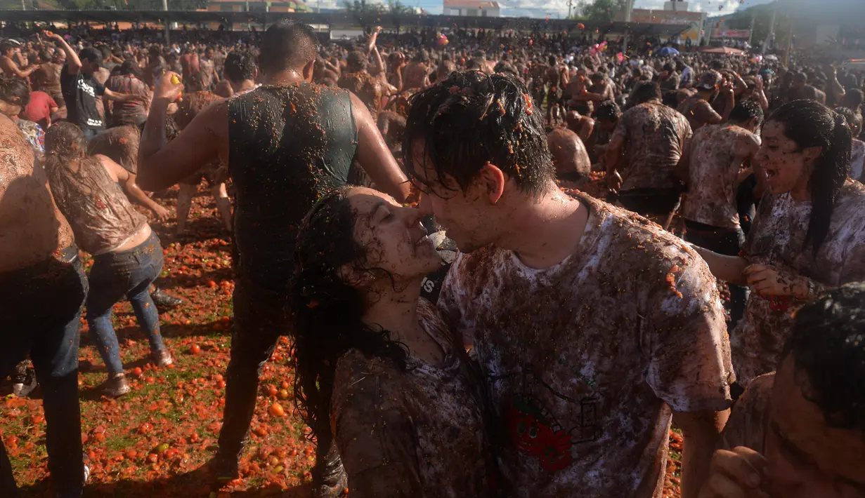 Sepasang peserta perang tomat bermesraan saat berlangsungnya Festival Tomatina di Sutamarchan, Boyaca, Kolombia, Minggu (2/6/2019). Festival Tomatina ini sudah memasuki tahun ke-10. (Diana SANCHEZ/AFP)