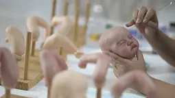 Seniman Brasil Ana Paula Guimaraes mengerjakan boneka bayi super realistis di studionya di Contagem, pada 16 November 2021. Boneka bernama Reborn Babies ini menampilkan detail seperti kuku, bulu mata, urat, lipatan, dan bintik-bintik di tubuh yang terlihat seperti bayi sungguhan. (DOUGLAS MAGNO/AFP)
