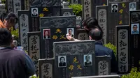 Peziarah membersihkan batu nisan keluarga mereka untuk menyambut festival Ching Ming dikomplek pemakaman di Shanghai (3/4). Mereka berdoa di depan nenek moyang, menyapu pusara dan bersembahyang. (AFP/Johannes Eisele)