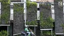 Pengemudi ojek online melintas di depan taman vertikal kawasan Tugu Tani, Jakarta Pusat, Senin (17/7). Tanaman hias yang dulu yang berjajar indah dan asri, kini banyak yang mati sehingga mengganggu keindahan kota. (Liputan6.com/Immanuel Antonius)