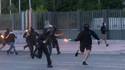 Pengunjuk rasa bersiap melemparkan bom molotov ke arah polisi antihuru-hara saat unjuk rasa terkait kematian warga Afrika-Amerika yang bernama George Floyd di Athena, 3 Juni 2020. Ribuan orang ambil bagian dalam unjuk rasa di ibu kota Yunani pada Rabu (3/6) atas kematian Floyd. (Xinhua/Marios Lolos)
