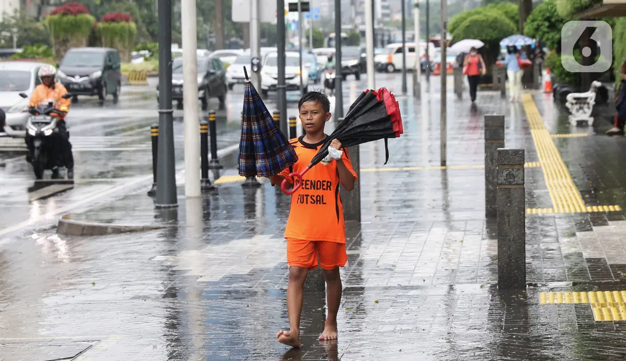 Seorang anak menawarkan jasa ojek payung di tengah hujan yang turun di kawasan Bundaran HI, Jakarta, Senin (3/2/2020). Hujan deras yang mengguyur sejumlah wilayah di DKI Jakarta dimanfaatkan para pengojek payung untuk mencari penghasilan tambahan. (Liputan6.com/Angga Yuniar)