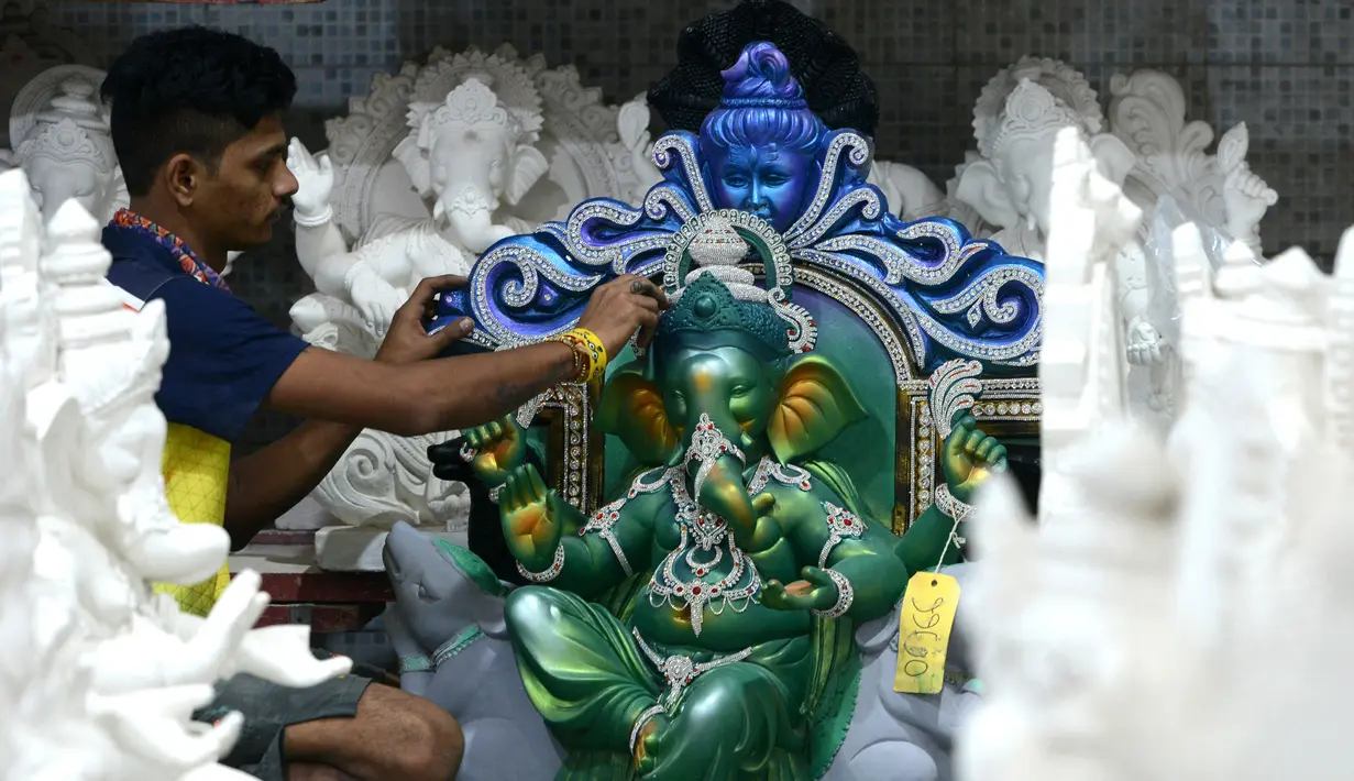Seorang perajin memberikan sentuhan terakhir saat pembuatan patung Dewa Ganesha di sebuah bengkel di Mumbai, India, 24 Agustus 2021. Pembuatan patung dewa Hindu berkepala gajah tersebut dilakukan jelang Festival Ganesh Chaturthi. (SUJIT JAISWAL/AFP)
