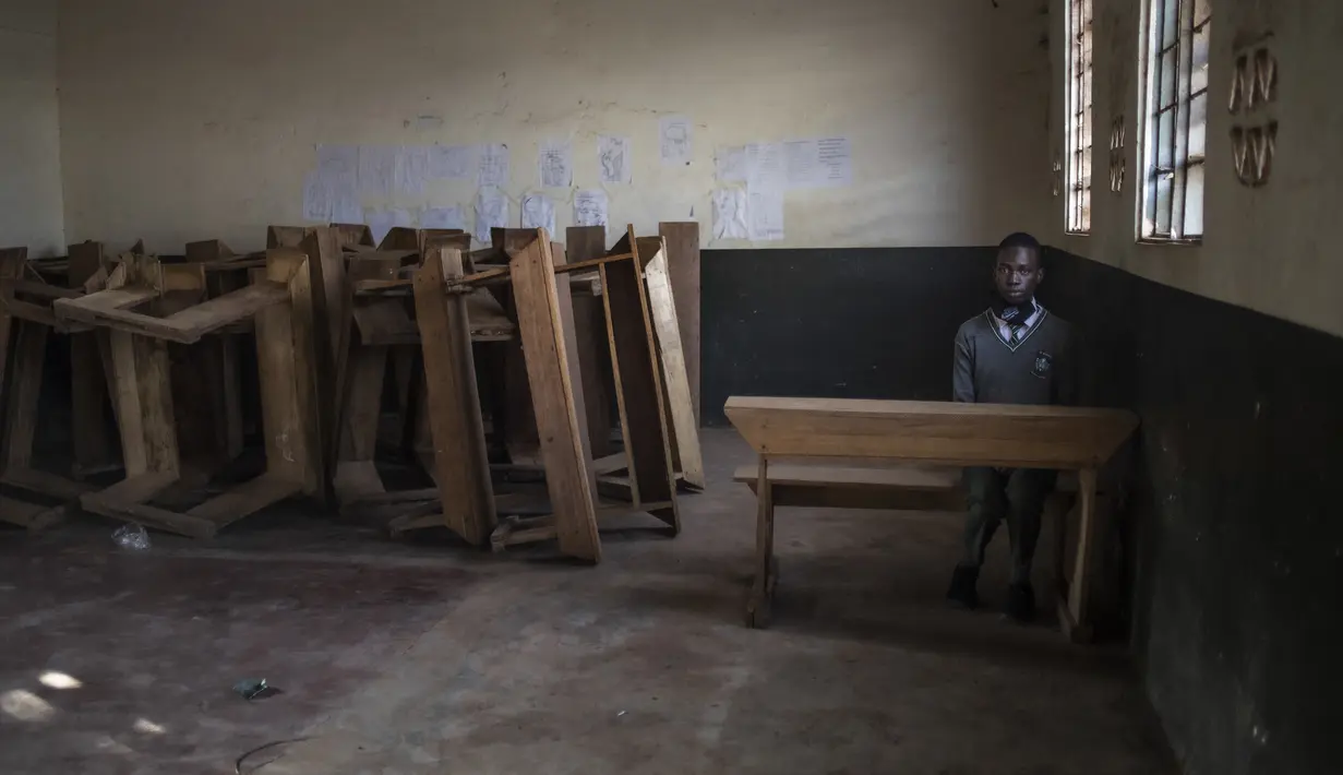 Seorang siswa duduk sendirian di ruang kelas setelah melapor pada hari pertama pembukaan kembali sekolah di Kampala pada 10 Januari 2022. Sekolah-sekolah di Uganda dibuka kembali untuk siswa pada Senin (10/1), mengakhiri penutupan sekolah terlama di dunia akibat pandemi COVID-19. (Badru KATUMBA/AFP)