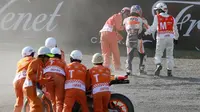 Pebalap Repsol Honda, Dani Pedrosa, mendapat bantuan dari marshal dan staf medis untuk berjalan keluar trek setelah mengalami kecelakaan hebat pada sesi latihan bebas kedua MotoGP Jepang di Twin Ring Motegi, Jumat (14/10/2016). (Crash)