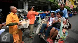 Juru parkir membagikan nasi bungkus kepada warga di jalan Malioboro,Yogyakarta, Jumat (11/3). Dalam aksinya mereka meminta dukungan kepada pengguna jalan yang melintas dan menuntut kejelasan relokasi yang bernurani. (Liputan6.com/Boy Harjanto)