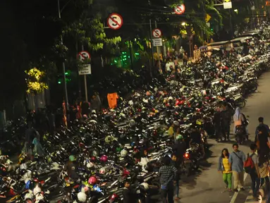 Warga berjalan di sisi deretan motor yang terparkir di ruas jalan Medan Merdeka Timur, Jakarta, Minggu (31/12). Akibat banyaknya motor yang parkir, ruas jalan Medan Merdeka Timur menyempit dan terjadi kemacetan panjang. (Liputan6.com/Helmi Fithriansyah)