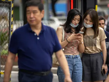 Dua perempuan melihat smartphone saat mereka berdiri di sudut jalan di Beijing, Rabu (6/7/2022). Warga beberapa bagian Shanghai dan Beijing telah diperintahkan untuk menjalani tes massal COVID-19 lebih lanjut menyusul ditemukannya kasus baru di dua kota, sementara pembatasan tambahan tetap berlaku di Hong Kong, Makau, dan kota-kota lain. (AP Photo/Mark Schiefelbein)