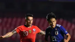 Gelandang Jepang, Takefusa Kubo menggiring bola dari kawalan pemain Chile, Charles Aranguiz selama pertandingan grup C Copa America 2019 di Stadion Morumbi, Sao Paulo, Brasil (17/6/2019). Kubo resmi dikontrak selama enam tahun oleh Real Madrid. (AFP Photo/Nelson Almeida)