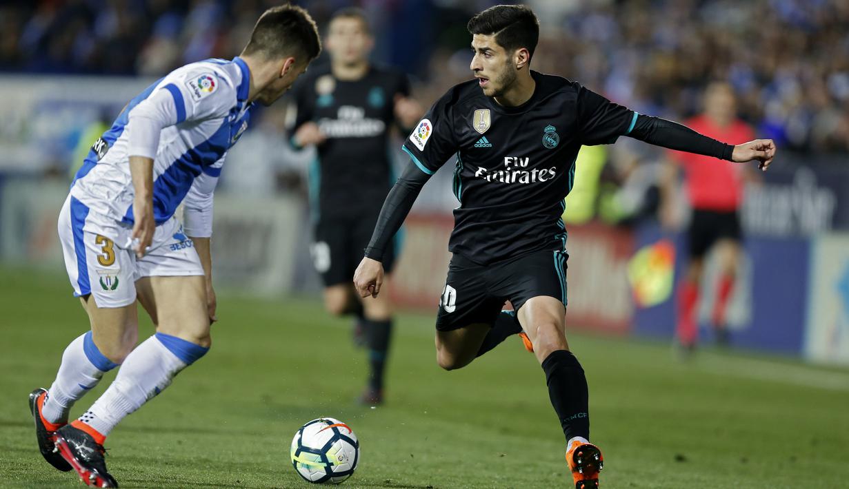 Aksi pemain Real Madrid, Marco Asensio (kanan) mengecoh pemain Leganes, Unai Bustinza pada lanjutan La Liga Santander di Butarque stadium, Leganes, (21/2/2018). Real Madrid menang 3-1.  (AP/Francisco Seco)