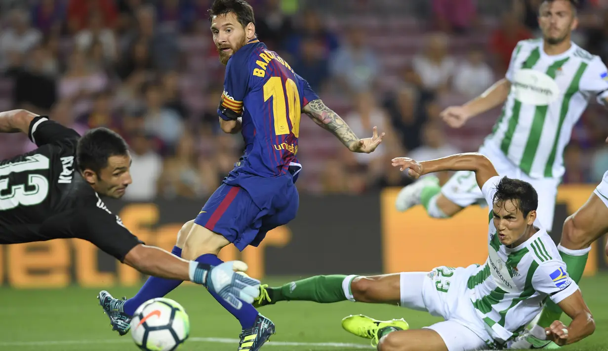 Lionel Messi (tengah) mengecoh kiper dan pemain Real Betis saat melakukan tembakan ke arah gawang pada lanjutan La Liga Spanyol di Camp Nou stadium, Barcelona, (20/8/2017). Barcelona menang 2-0. (AFP/Lluis Gene)