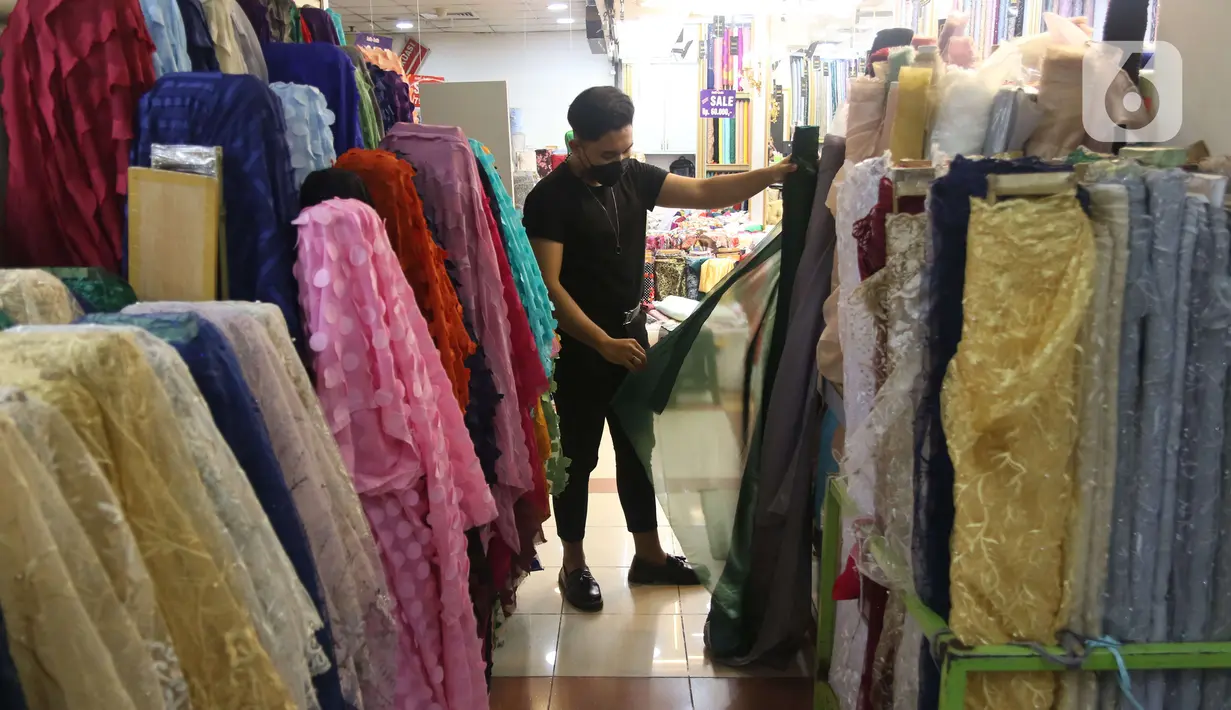 Pekerja menata bahan kain di Pasar Tanah Abang, Jakarta, Sabtu (27/11/2021). Utilisasi industri tekstil dan produk tekstil dalam negeri menunjukkan kinerja yang positif menjelang akhir 2021. Utilisasi industri itu berada di posisi 80 - 85 persen pada awal kuartal IV/2021. (Liputan6.com/Angga Yuniar)