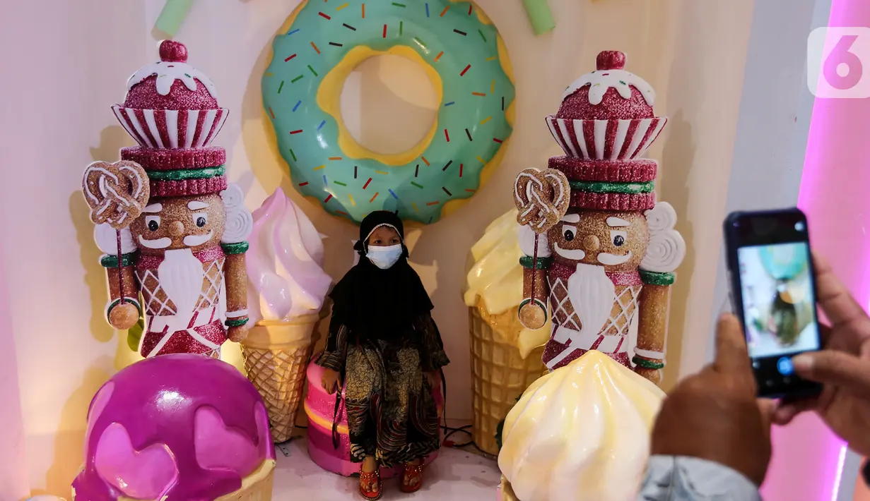 Pengunjung saat foto bernuansa candy land menjelang perayaan Natal 2021 di atrium Lippo Mall Puri, Jakarta, Minggu (5/12/2021). Dekorasi bertema Sweet Christmas yang didominasi warna putih dan pink juga dihiasi dengan pohon natal   setinggi 5 meter. (Liputan6.com/Fery Pradolo)