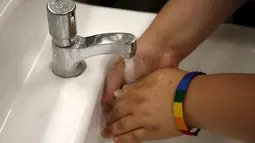 Seorang siswa mencuci tangan di toilet netral gender pertama di Santee High School, Los Angeles, California, AS, Senin (18/4). Toilet disediakan sebagai langkah mendukung dan menampung siswa transgender. (REUTERS/Lucy Nicholson)