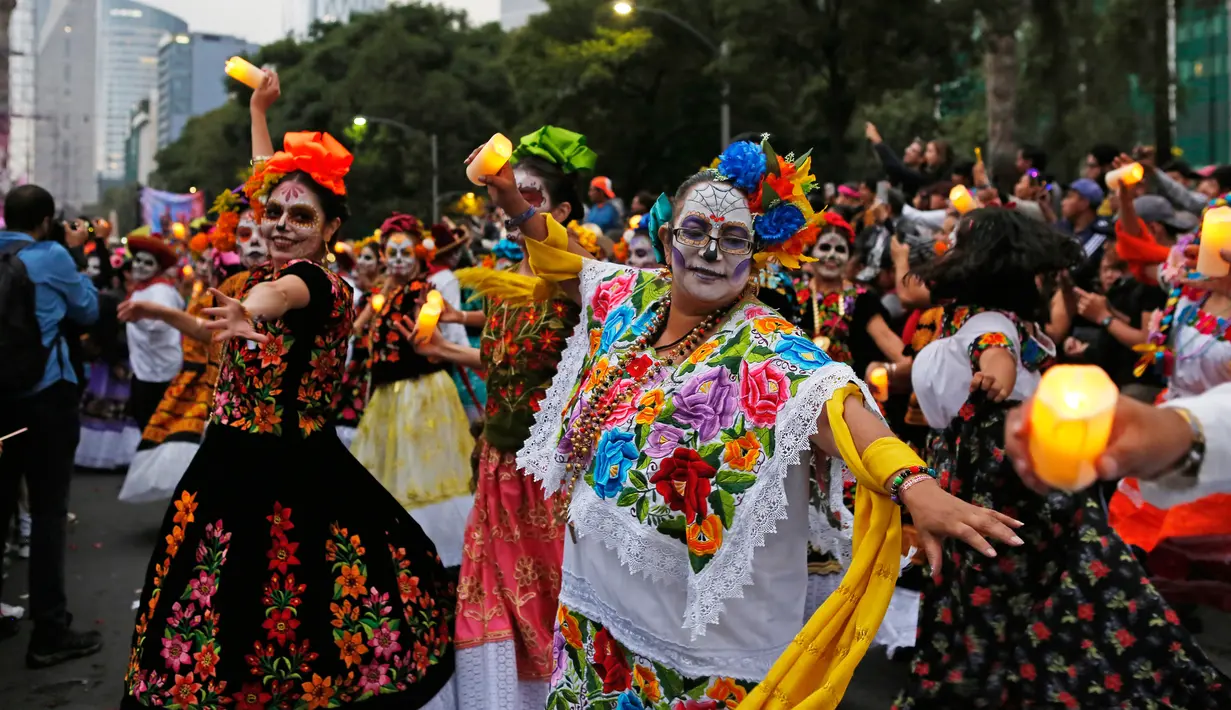 Peserta yang berdandan ala tengkorak menari saat mengikuti parade Hari Orang Mati di Mexico City, Meksiko, Sabtu (26/10/2019. Para peserta dalam parade ini mengenakan kostum dan melukis wajah mirip dengan tokoh tengkorak Meksiko yang ikonik, Catrina. (AP Photo/Ginnette Riquelme)