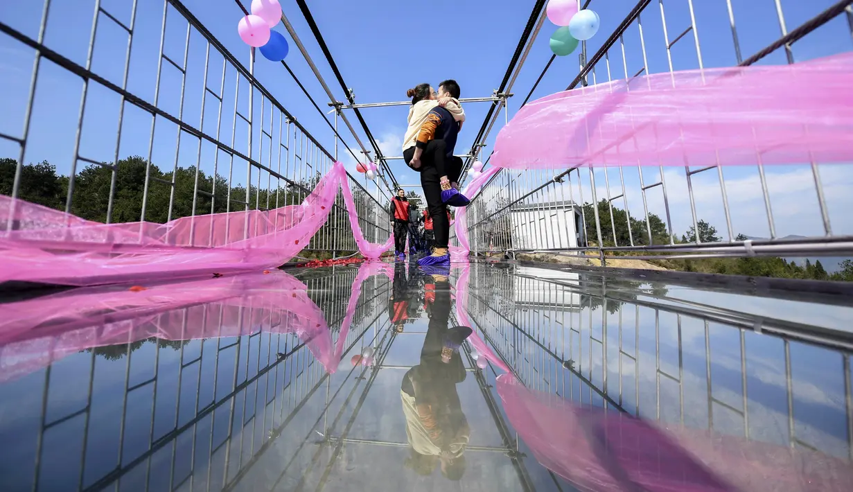 Sepasang pria dan wanita berciuman diatas sebuah jembatan kaca saat mengikuti kontes berciuman di Hari Valentine di Pingjiang, Provinsi Hunan, China (14/2). (STR / AFP)