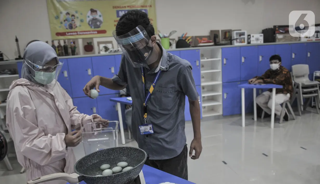 Terapis atau pengajar membimbing mahasiswa berkebutuhan merebus telur asin saat kelas terapi mata kuliah wirausaha di Lembaga Pendidikan dan Keterampilan Kampusnya Manusia, Kranggan, Bekasi, Jawa Barat, Kamis (3/12/2020). (merdeka.com/Iqbal S. Nugroho)