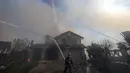 Petugas pemadam kebakaran memadamkan sebuah rumah yang terbakar di Whittier, California (10/2/2022). Setidaknya dua rumah hancur dalam kebakaran semak yang menghitamkan sekitar empat hektar di daerah Whittier. (AP Photo/Ringo H.W. Chiu)