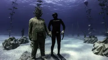 Penyelam bebas Angels Savvas berpose dengan patung di taman patung bawah laut MUSAM, Ayia Napa, Siprus, 18 September 2021. MUSAM disebut sebagai hutan bawah laut pertama di dunia. (EMILY IRVING-SWIFT/AFP)