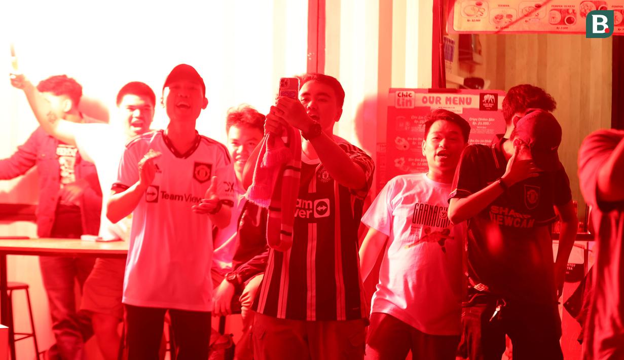 Anggota IndoManutd menyalakan suar saat Rasmus Hojlund mencetak gol pertama timnya saat acara Roaring Night antara Manchester United melawan  West Ham di Pitch 98, Kemang, Jakarta, Minggu (04/02/2024) malam WIB. (Bola.com/Abdul Aziz)