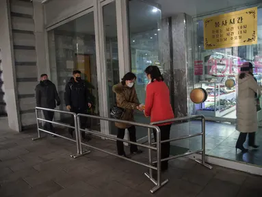 Petugas menyemprotkan sanitizer ke pengunjung di dalam Pyongyang Department Store No. 1, Korea Utara (28/12/2020). Meski Korea Utara melaporkan nol kasus Covid-19, pemerintahan Pyongyang tetap menerapkan standar protokol kesehatan guna mencegah penyebaran Covid-19. (AFP/Kim Won Jin)